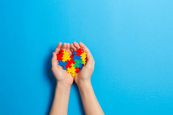 Foto colorida de cordão colorido com quebra-cabeça, simbolizando autismo, condição do aluno que teve a inscrição no intercâmbio negada - Metrópoles