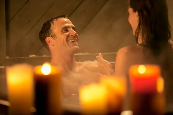 Casal na banheira com velas acesas em volta - Metrópoles