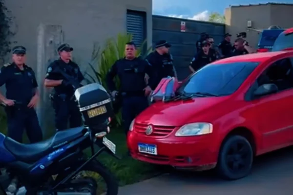Imagem colorida de GCMs e um carro vermelho. Metrópoles
