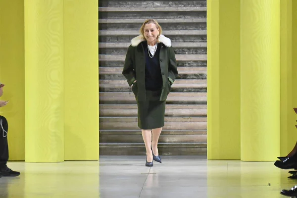 A imagem mostra a designer Miuccia Prada andando na passarela