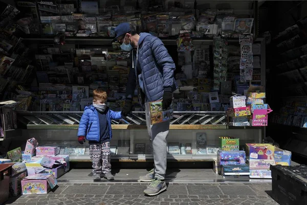 Pai e filho em livraria na Itália durante pandemia do coronavírus