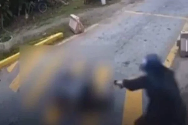 Foto colorida que mostra o atirador disparando diversas vezes contra o homem, na porta de um condomínio em SP
