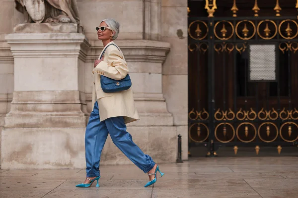 Look com macacão azul acetinado, scarpin azul e bolsa azul, além de blazer branco, no street style