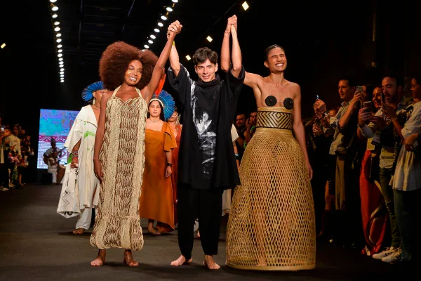 Estilista indígena segurando as mãos de modelo indígena e Thelma Assis - Metrópoles