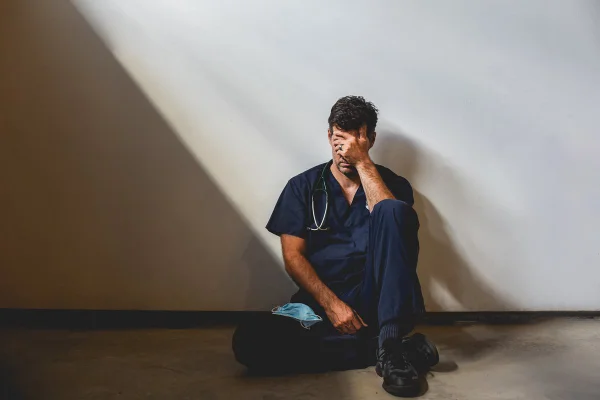 Foto colorida de um homem sentado, encostado na parece com luzes distorcidas - Metrópoles
