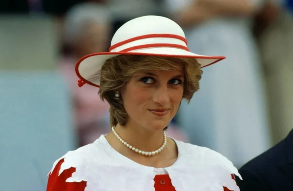 Foto colorida de uma mulher loira usando um vestido branco e vermelho e chapéu nas mesmas cores