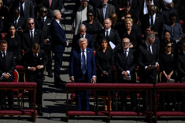 A imagem msotra o presidente dos Estados Unidos, Donald Trump, ao lado de Melania Trump e um homem durante o velório do papa Francisco
