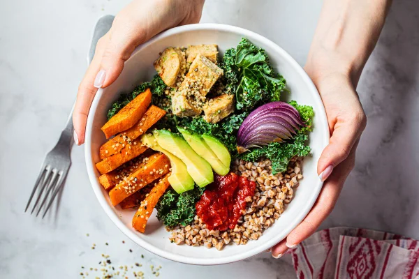 mãos de uma mulher segurando um bowl branco com alimentos