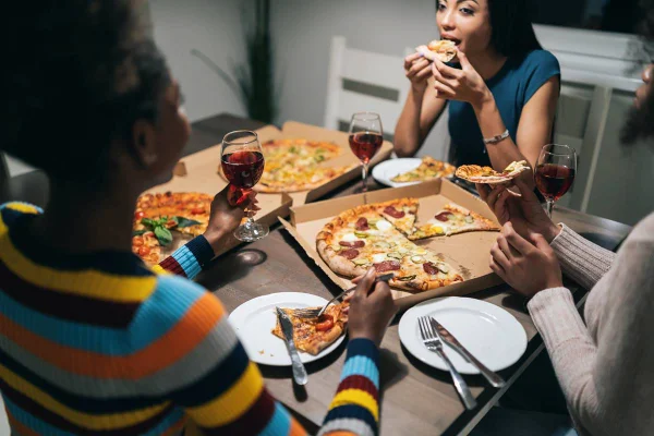 Amigos comendo pizza e tomando vinho no jantar
