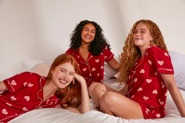 três meninas deitadas na cama vestidas com pijamas vermelhos