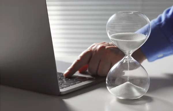 Foto mostra homem acionando teclas de um computador com uma ampulheta a seu lado. - Metrópoles - inteligência artificial prevê morte