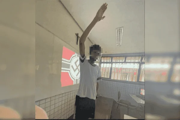 Aluno faz gesto nazista diante de quadro com a bandeira nazista projetada em sala de aula no colégio Ciman - Metrópoles