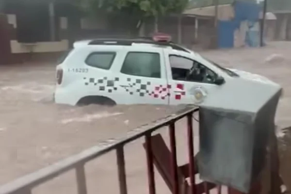 Imagem colorida de viatura policial no meio de enxurrada. Metrópoles