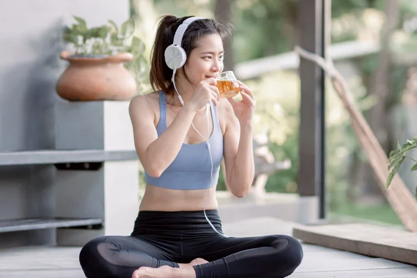 Imagem de uma mulher jovem de roupa de academia tomando chá - Metrópoles