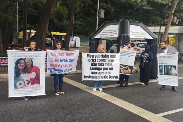 Imagem colorida de mulheres segurando faixas de protesto contra as Testemunhas de Jeová. Metrópoles