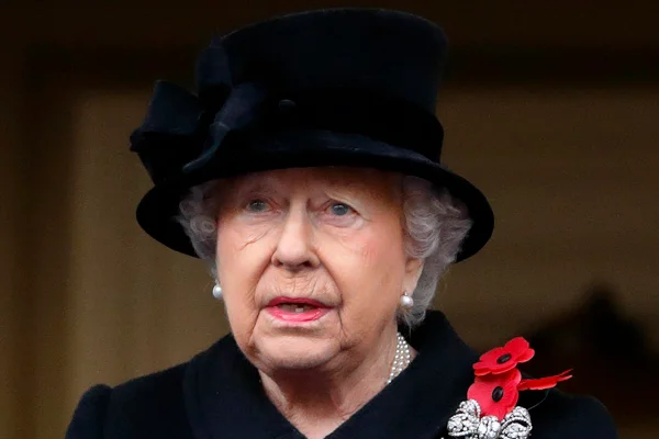 Mulher idosa chorando. Ela veste roupas pretas e usa um broche com flores vermelhas