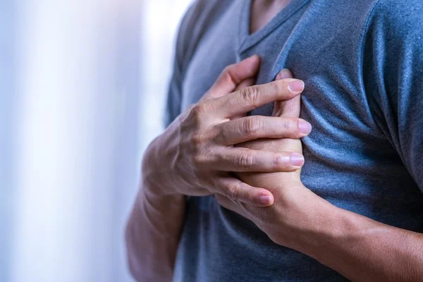 Homem coloca as mãos ao peito, com dor. Ele veste blusa azul-Metrópoles