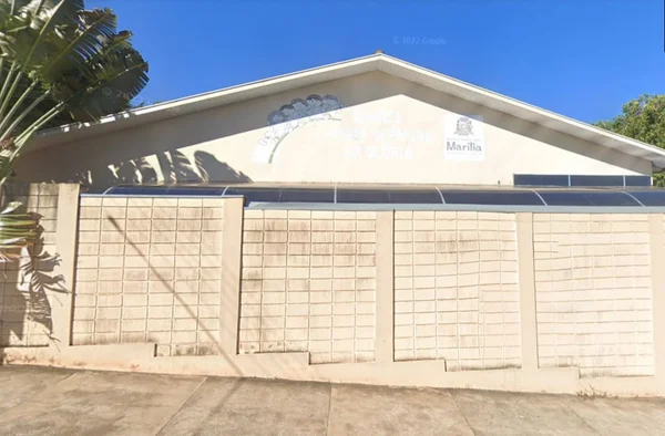 Imagem colorida de fachada de creche pintada de bege; um muro e um telhado aparecem na entrada - Metrópoles