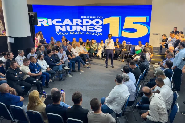 Imagem colorida mostra grupo de pessoas sentadas em círculo com Ricardo Nunes em pé, no centro, falando ao microfone - Metrópoles