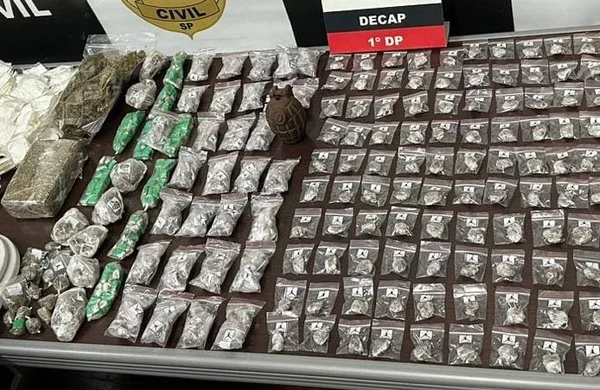 Foto colorida de pequenas embalagens plásticas com drogas espalhados sobre uma mesa; no centro, em destaque, uma granada marrom escuro - Metrópoles