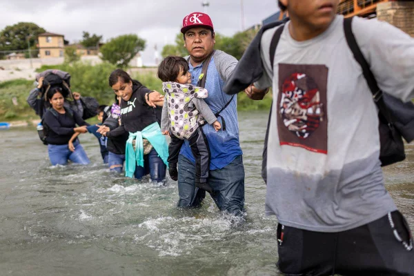 Imagem colorida mostra imigrantes venezuelanos em um rio - Metrópoles
