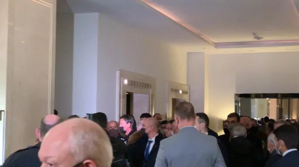 Bolsonaro deixa hotel de máscara em Moscou, Rússia. Ele está no centro da imagem, cercado por uma aglomeração de assessores e jornalistas - Metrópoles