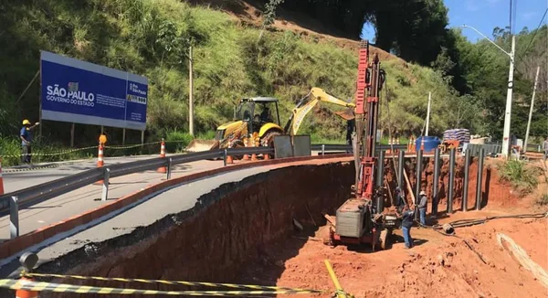 Imagem colorida de obra em rodovia parcialmente destruída com máquinas operando na terra - metrópoles