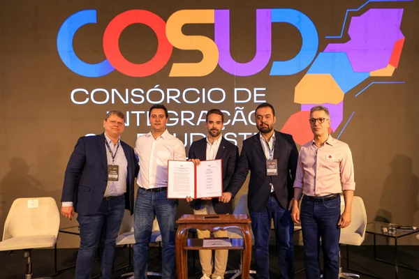 Imagem mostra homens segurando documento em evento - Metrópoles