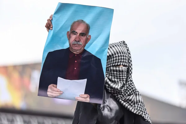 Imagem colorida mostra homem segurando foto do fundador do PKK - Metrópoles