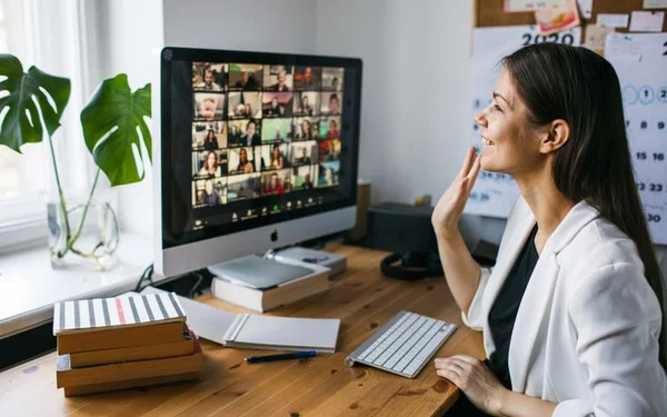 Mulher sentada em frente a um computador com a mão erguida