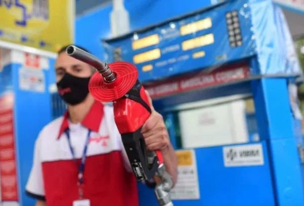 Frentista segurando mangueira de bomba de gasolina- Metrópoles