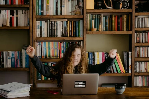 mulher branca estudando em frente a uma prateleira cheia de livros