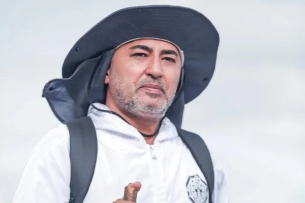 Foto colorida de homem usando blusa branca e chapeu preto - Metrópoles.