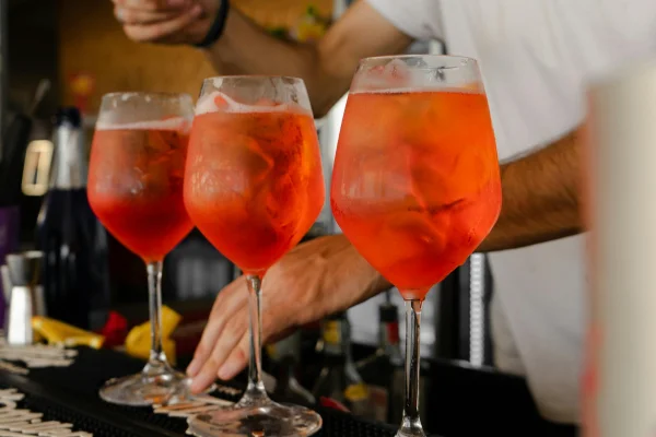 Três taças servidas com o drink Aperol Spritz