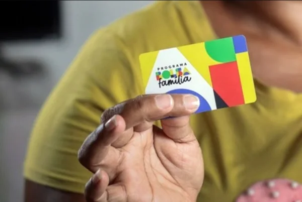 Mão segurando um cartão do Bolsa Família - Metrópoles
