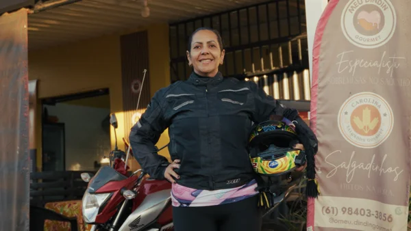 Foto colorida de uma mulher ao lado de uma moto - Metrópoles