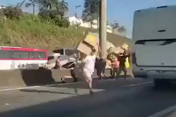 Imagem colorida de homem correndo com caixa de papelão em meio à rodovia - Metrópoles