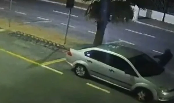 Imagem colorida mostra homem vestido de preto abordando carro cinza com empresário; motorista foi morto com 3 tiros - Metrópoles