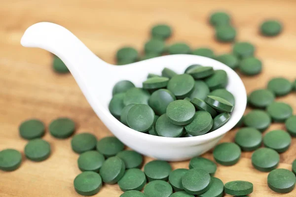 Imagem mostra vários comprimidos de spirulina em uma concha branca - Metrópoles