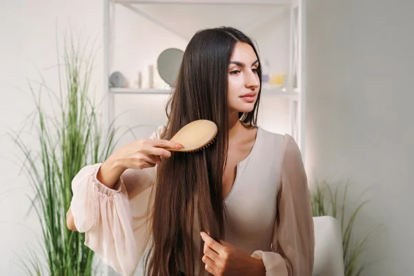foto colorida mulher escovando seus fios fortes e longos