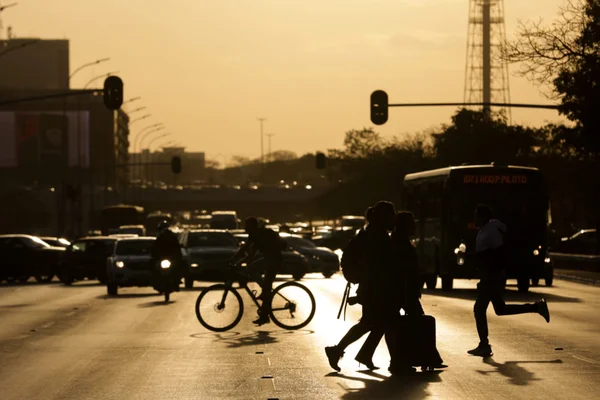 pessoas caminham no por do sol em período de seca e baixa humidade em brasília df