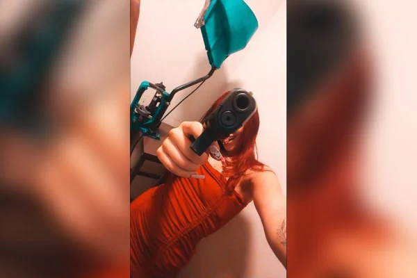 Mulher ruiva apontando arma