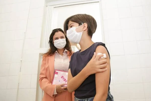 Criança segura algodão no braço após vacinação
