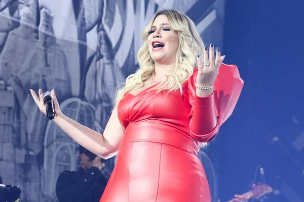 Marília Mendonça de macacão vermelho em show na cidade de São Paulo