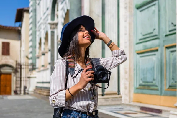 Mulher morena está admirando um ponto turístico com uma câmera fotográfica nas mãos - Metrópoles