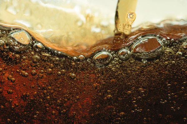 Imagem mostra refrigerante escuro com bolhas visto de perto - Metrópoles