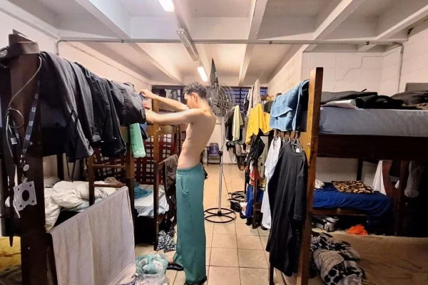 Rapaz coloca camisa dentro de quarto do alojamento