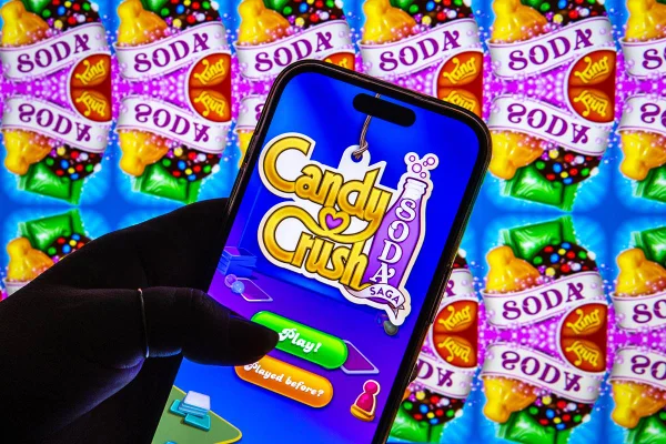 Imagem colorida mostra pessoa com celular na mão, jogando o jogo Candy Crush - Metrópoles
