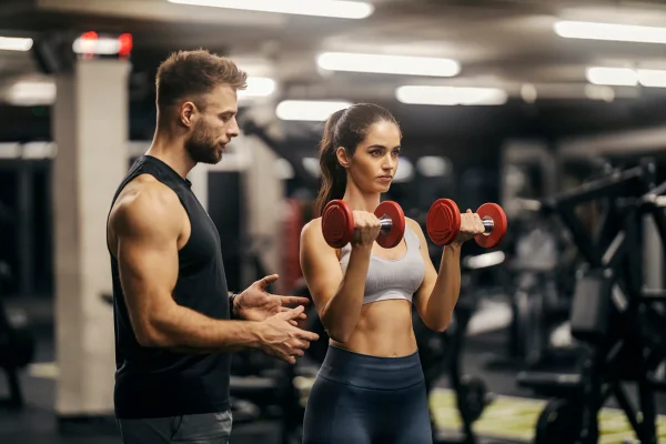 Homens instrui mulher em treino na academia - Metrópoles