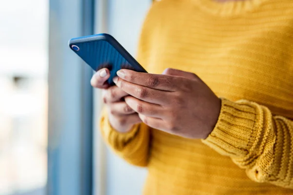 Foto colorida de uma mulher mexendo no celular - Metrópoles